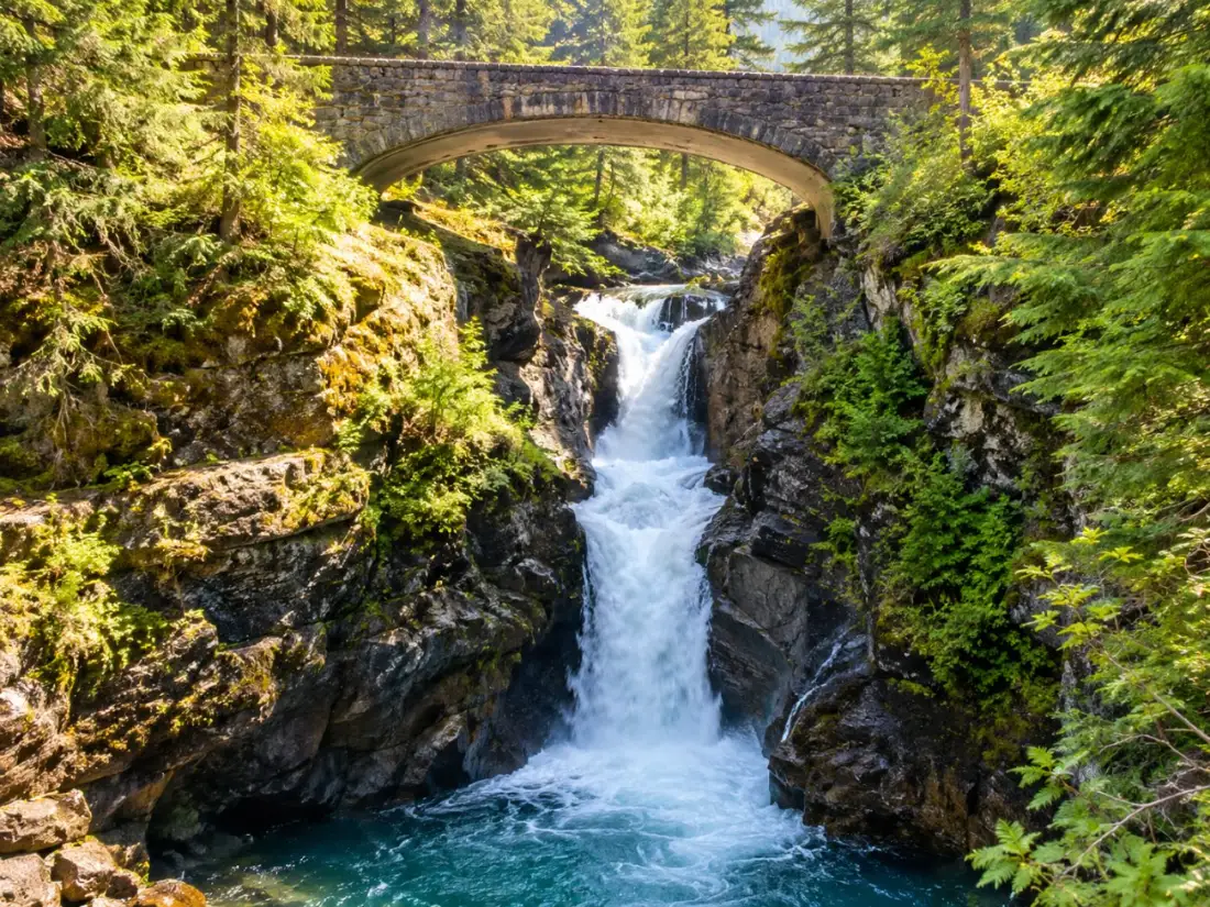 Christine Falls dropping beneath an old stone road bridge in the forest