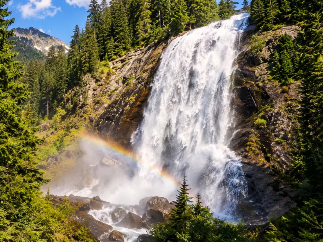 Narada Falls pouring down a broad rock face in a spray of mist